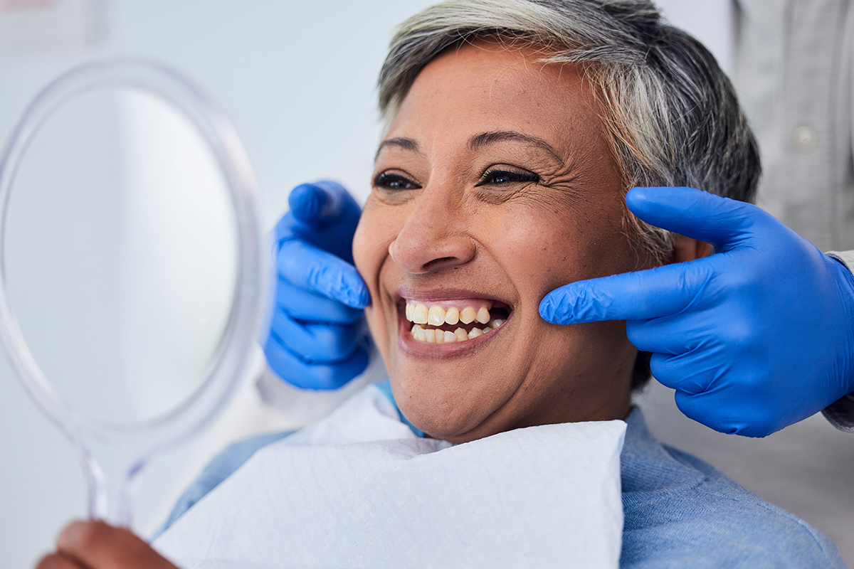 Smiling patient receiving dental care with hygienist's assistance, showcasing professional teeth cleaning at Palani Center for Dental Implants.