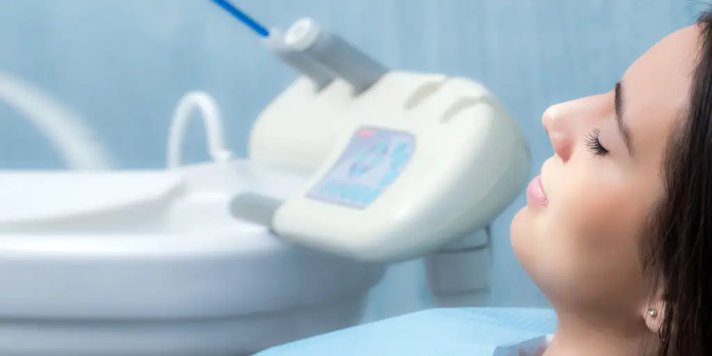 Patient relaxing in dental chair with sedation equipment in background, reflecting post-sedation phase of full mouth restoration procedure at Palani Center for Dental Implants.